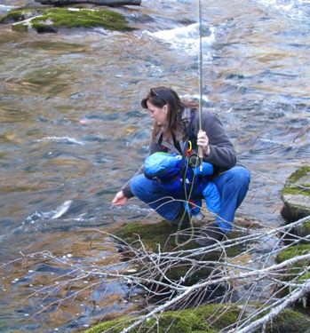 Charity lands a nice rainbow. Notice she's toting our sleeping son in a chest pack and restricted to fishing from the bank.